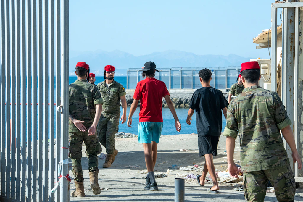 Spanische Soldaten begleiten zwei junge Männer im Grenzgebiet von Ceuta. Die Armee wurde eingesetzt, nachdem die örtlichen Sicherheitskräfte die Kontrolle verloren hatten.