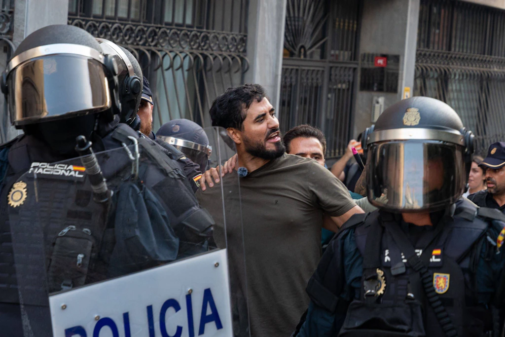Polizisten führen den spanischen Europaabgeordneten Luis Alvise Pérez aus dem Bereich einer Demonstration in Ceuta. Gegendemonstranten protestierten gegen einen angekündigten Aufmarsch migrationsfeindlicher Gruppen.