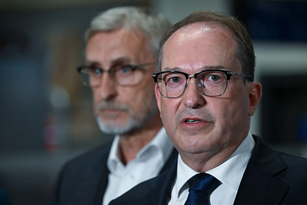 Bundesinnenminister Alexander Dobrindt (CSU, rechts) spricht bei einer Pressekonferenz in einem Terminal des Flughafens Leipzig/Halle. Hinter ihm steht Armin Schuster (CDU), Innenminister von Sachsen.