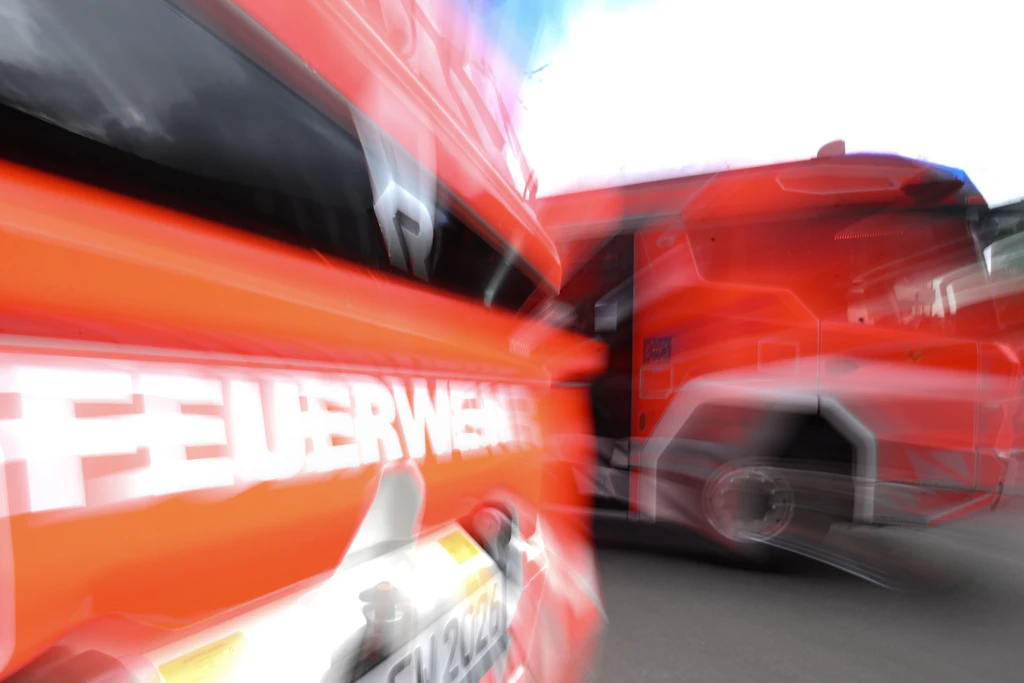 Zwei Einsatzfahrzeuge der Feuerwehr stehen vor einer Feuerwache zum Einsatz bereit.