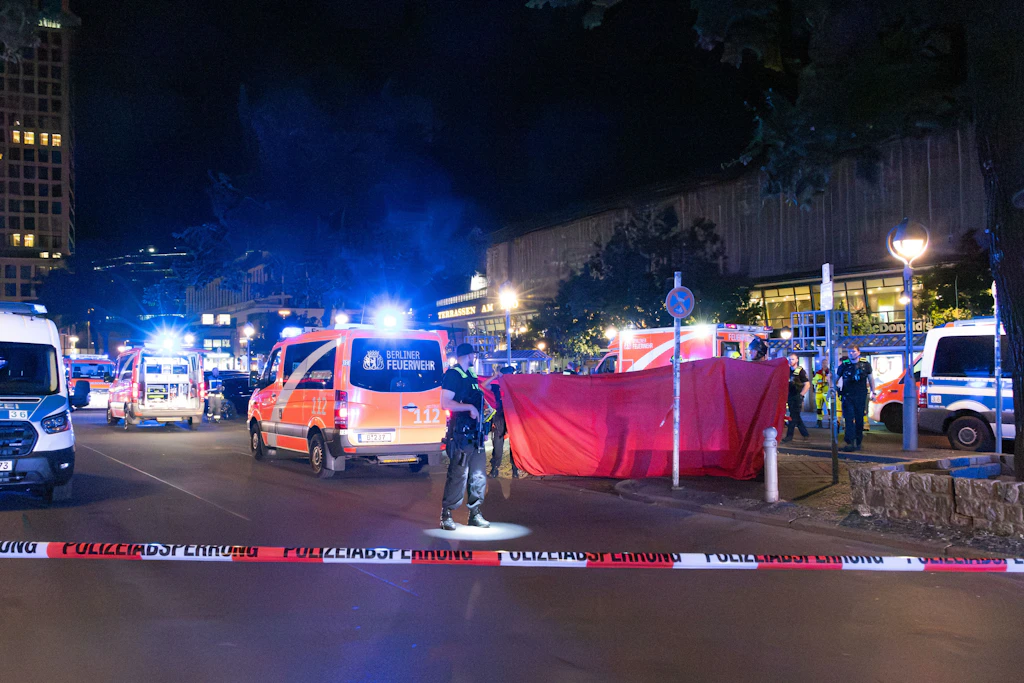 Einsatzkräfte von Polizei und Feuerwehr sichern in der Nacht den Tatort am Hardenbergplatz vor dem Bahnhof Zoologischer Garten; ein Sichtschutz schirmt den Bereich hinter der Absperrung ab.