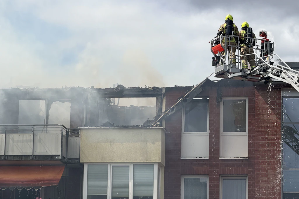 Von einer Drehleiter aus löschen Feuerwehrleute die Flammen.