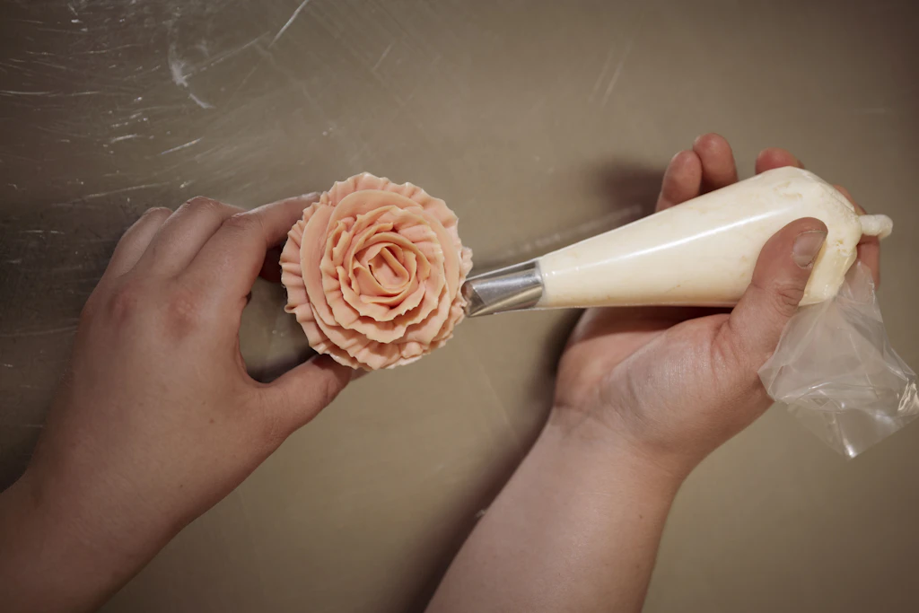 Auf die Schokoteig-Muffins wird die Blüte aus Buttercreme per Hand aufgespritzt.