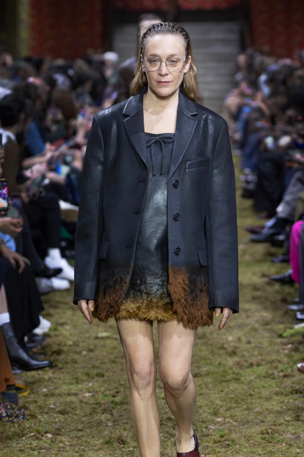 Schauspielerin Chloé Sevigny auf dem Miu-Miu-Laufsteg für Herbst/Winter 2026 – mit Zickzack-Haarreif im Haar.