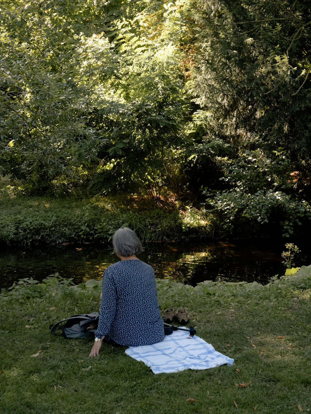 Dorothea F. sitzt im Schlosspark Pankow am Wasser.