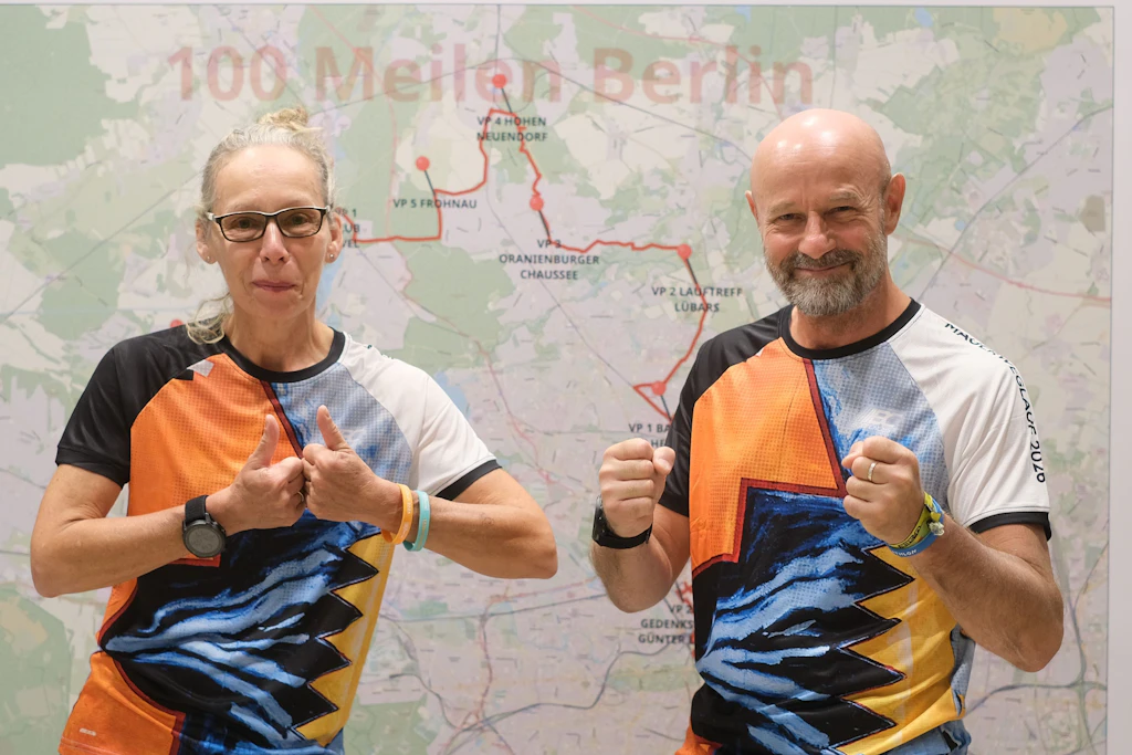 Antje Matthiesen und Jörn Künstner vor einer Streckenkarte des Mauerweglaufs