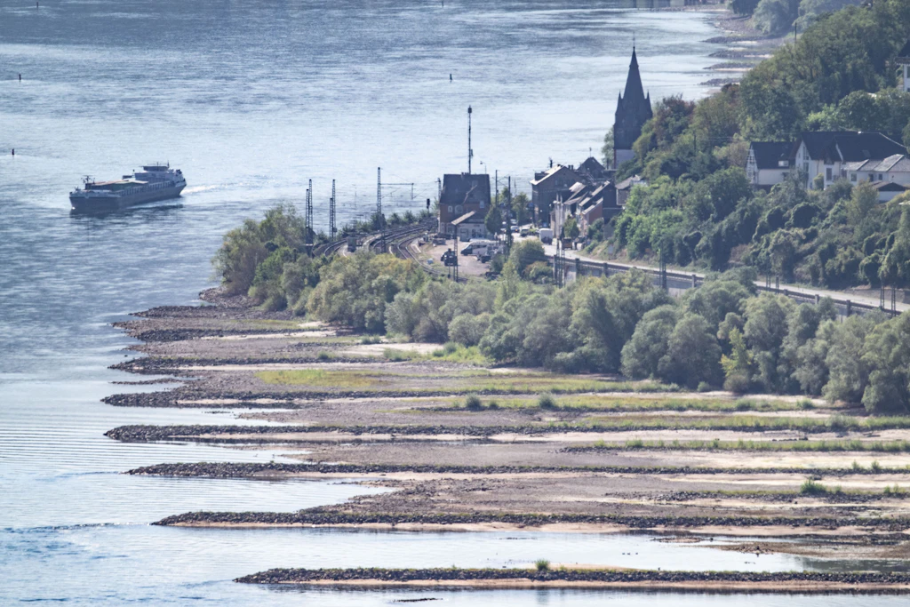 Ein Schiff fährt an frei liegenden Sandbänken auf dem Rhein bei Bacharach vorbei. Die Binnenschifffahrt ist bereits massiv eingeschränkt.