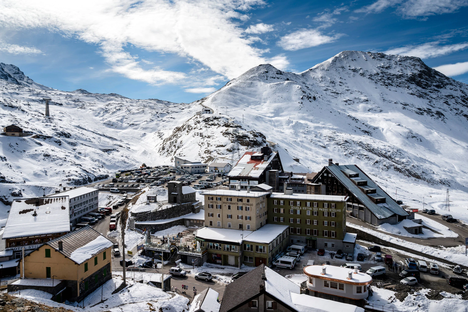 Die Passhöhe des Stilfser Jochs auf 2757 Metern mit Hotels, Parkplätzen und der Sommer-Skischule „Scuola Estiva Sci Passo Stelvio“.