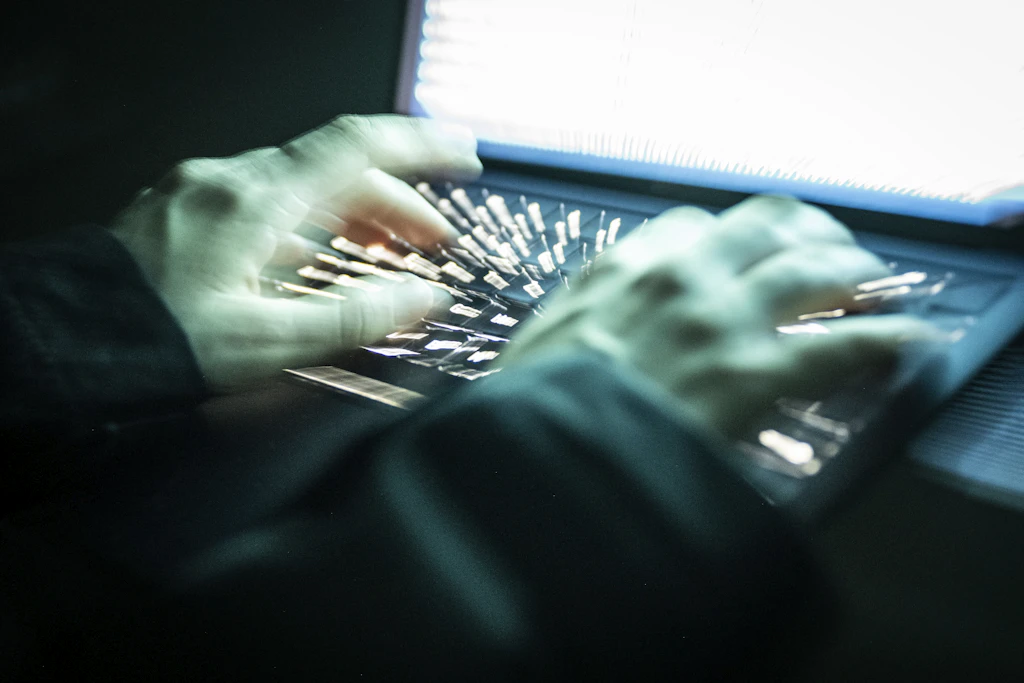 Eine Person tippt mit den Fingern auf einer beleuchteten Laptop-Tastatur.