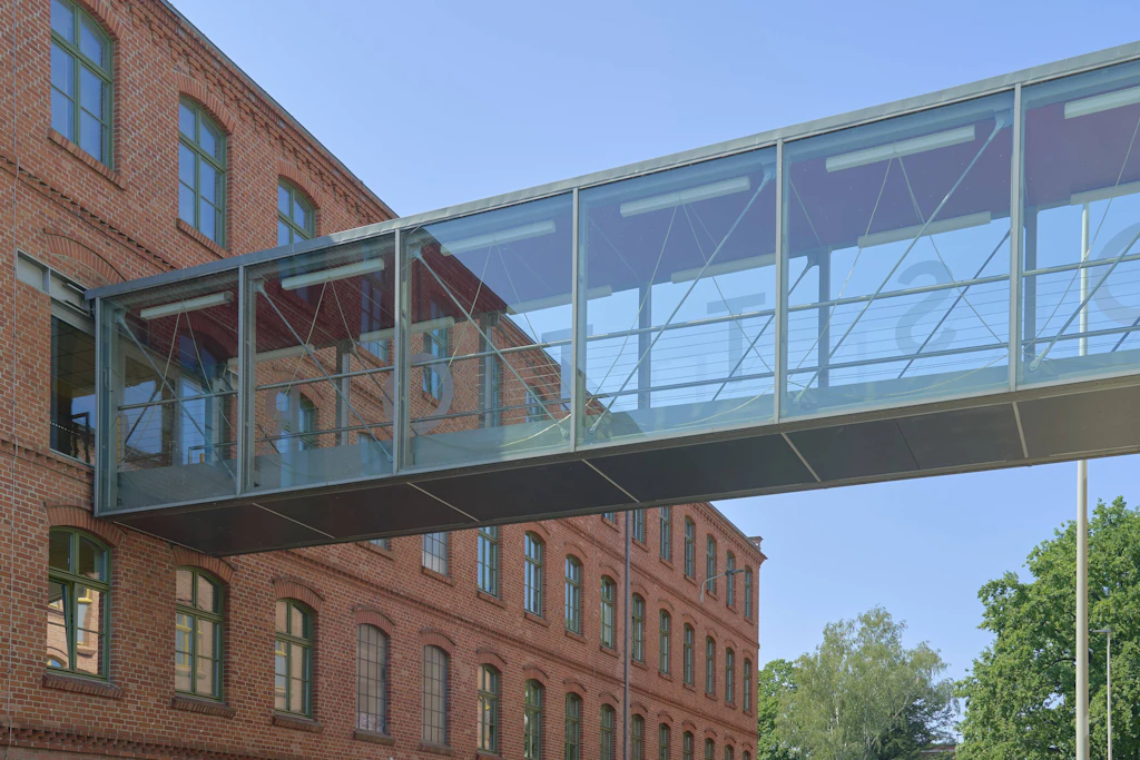 Postindustrieller Strukturwandel und architektonische Transformation in der Franz Mehring Straße in Cottbus Bundesland Brandenburg, eine verglaste Fußgängerbrücke verbindet zwei historische Backsteinbauten der ehemaligen Tuchfabrik als Sinnbild für die Symbiose von industriellem Erbe und akademische