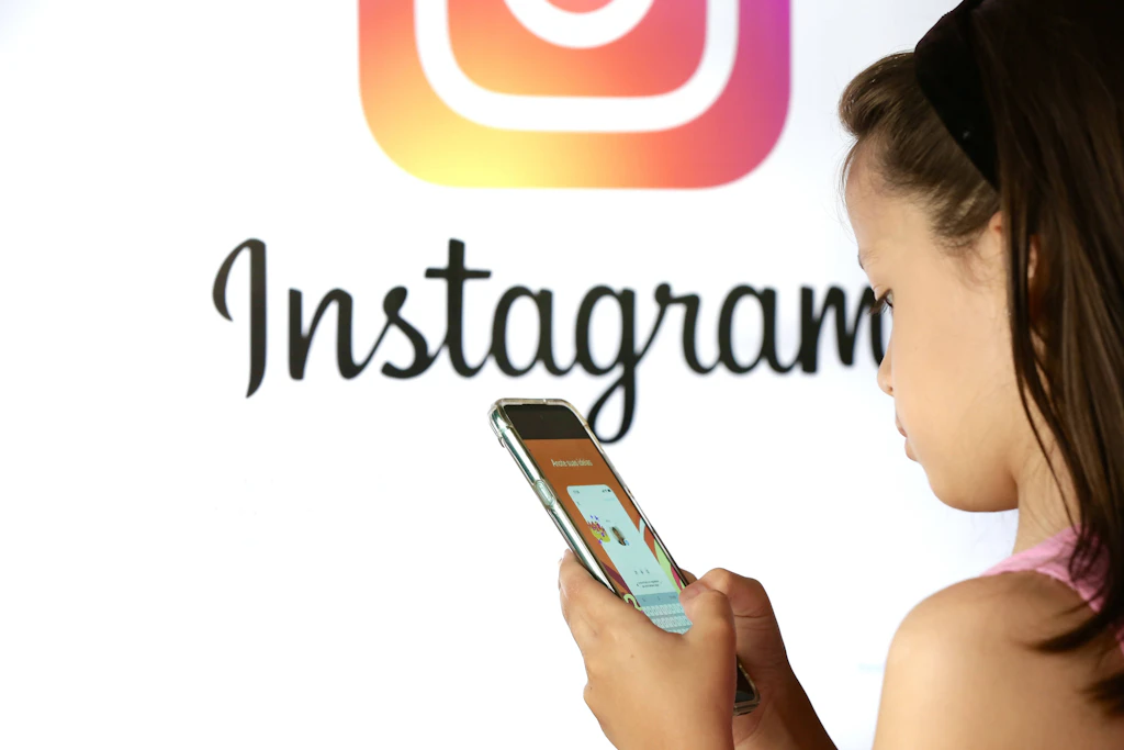 Ein Kind nutzt ein Smartphone vor dem Instagram-Logo. Gegen Meta läuft in den USA ein wegweisender Prozess über mögliche Schäden sozialer Medien für Minderjährige.