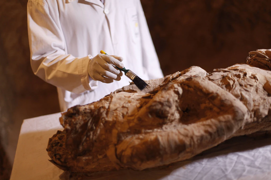 Ein Archäologe untersucht eine Mumie in einem Grab auf dem Westufer von Luxor, wo auch das in der Studie untersuchte Grab TT209 liegt.