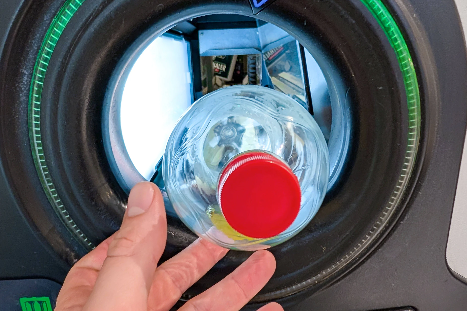 Eine PET-Pfandflasche wird in einen Pfandautomaten eingeführt und automatisch erfasst.