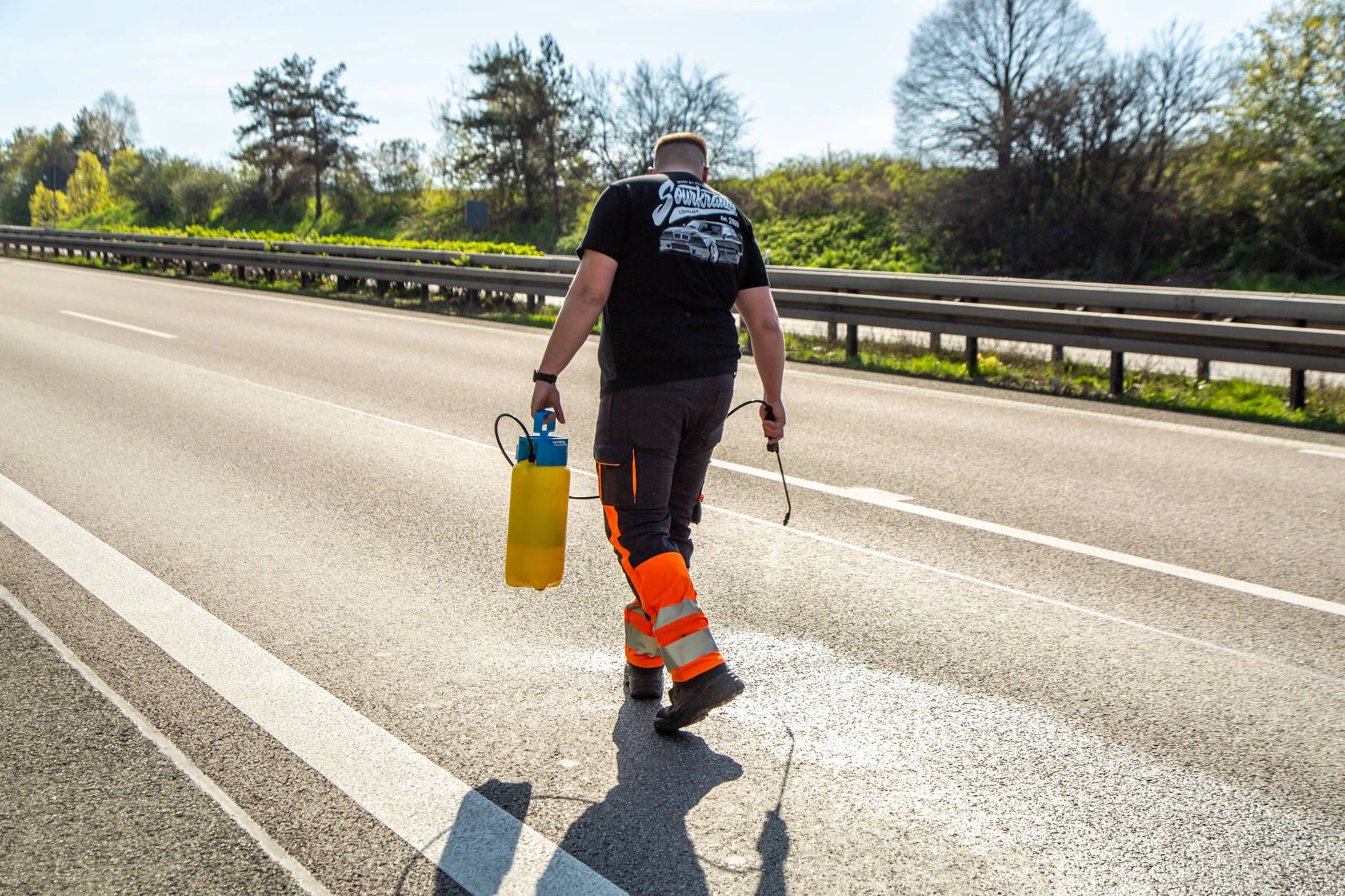 Ein Mitarbeiter des Straßenbetriebs läuft mit einer Handsprühflasche über eine gesperrte Autobahnfahrbahn – Fahrbahnarbeiten wie diese können sich über Stunden ziehen. (Symbolbild)