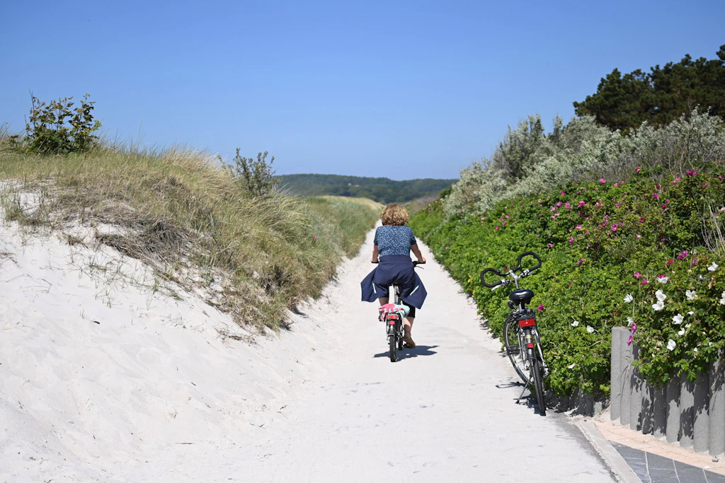 Eine Radfahrerin ist auf der Insel Hiddensee, am Strand von Vitte, unterwegs.