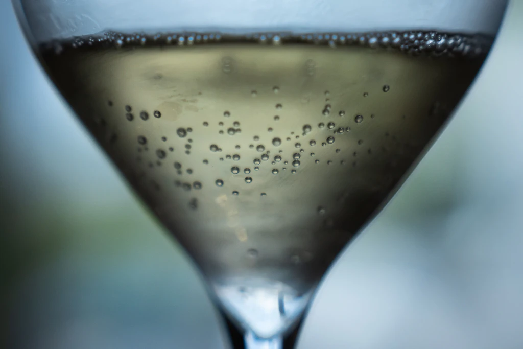 Kohlensäurebläschen steigen in einem Glas Champagner auf. Der Hitzesommer verändert den Jahrgang 2026.