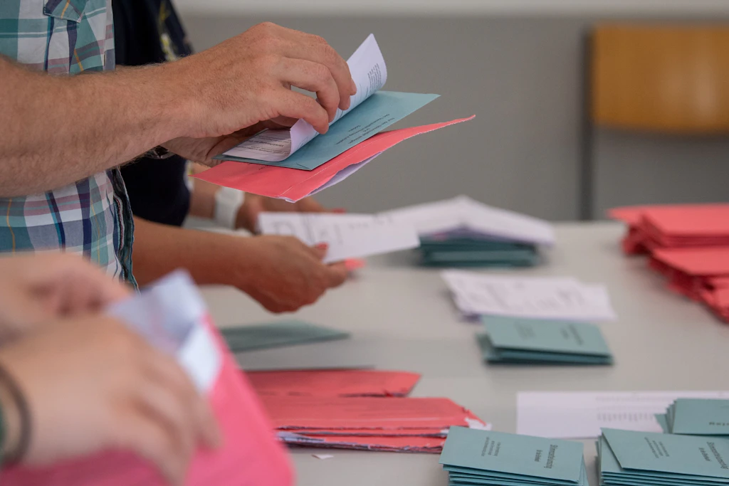 Wahlhelfer öffnen in einem Klassenzimmer einer Schule in Magdeburg die Umschläge der Briefwahl.