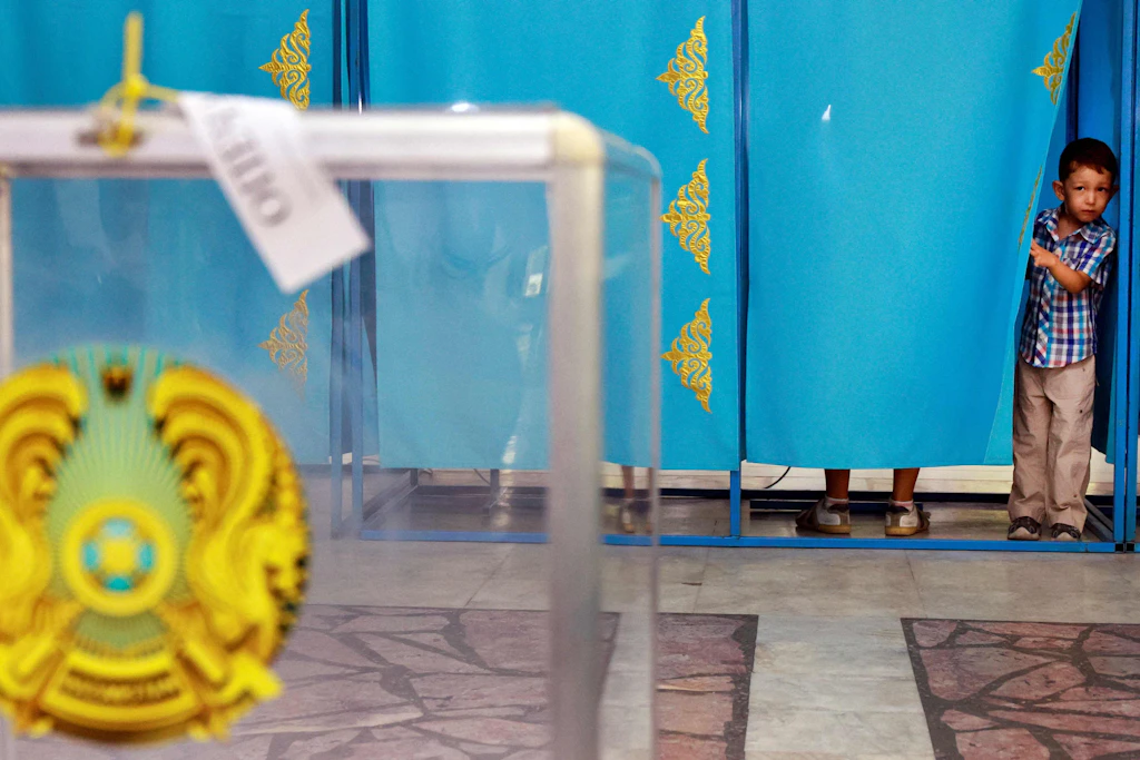 Ein Junge schaut aus einer Wahlkabine in Astana, während sein Vater seine Stimme abgibt.
