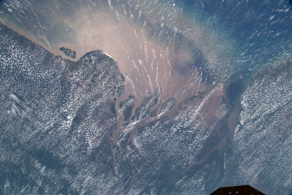 Der Amazonas mündet im Norden Brasiliens in den Atlantik. Sedimente färben das Wasser milchig braun, während Wolken über dem Bundesstaat Amapá ziehen.