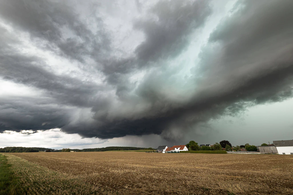 Eine Gewitterfront zieht über ein Dorf: Der Deutsche Wetterdienst erwartet am Dienstagnachmittag im Südwesten Starkregen, Hagel und stürmische Böen. (Symbolbild)