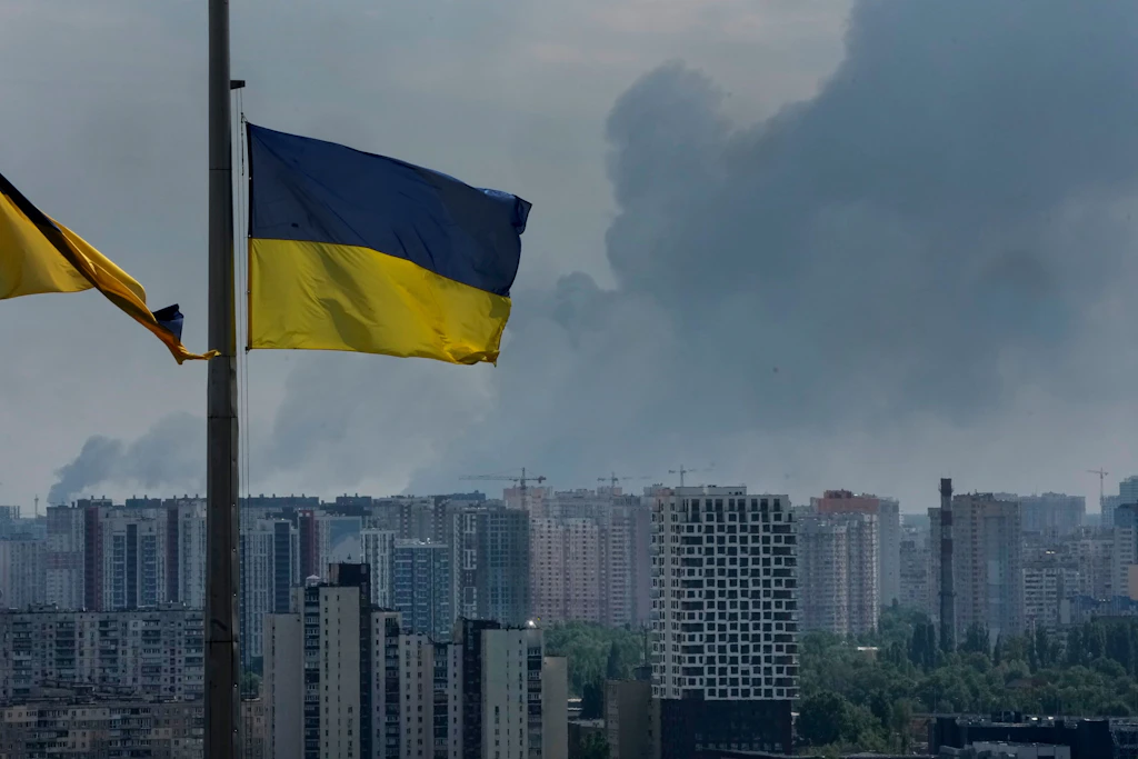 Ukrainische Flaggen wehen, während nach einem russischen Angriff auf Kiew Rauch über dem Stadtzentrum aufsteigt.