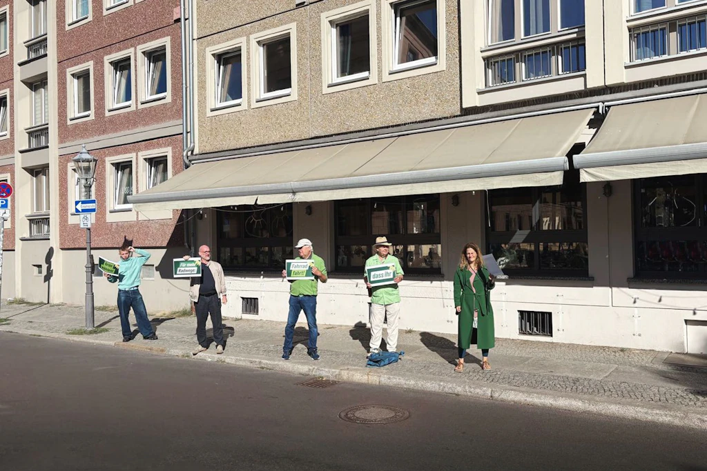 Grüne stehen am Straßenrand und applaudieren.