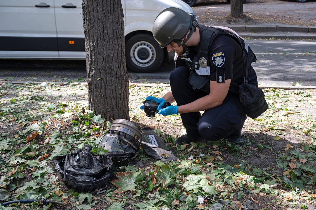 Ein Ermittler der ukrainischen Polizei dokumentiert Trümmer einer russischen Drohne an der Parkowa Doroha im Kiewer Bezirk Petschersk.