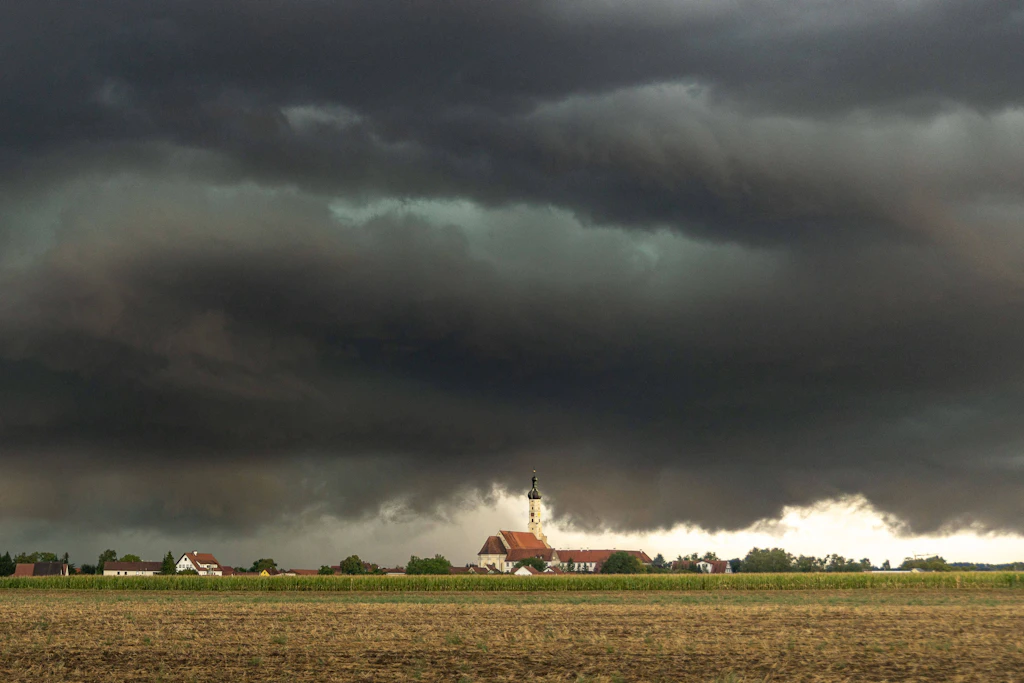 Gewitterfront über einem Dorf: Am Montag drohen Sturmböen bis 90 km/h, Starkregen und Hagel. (Symbolbild)
