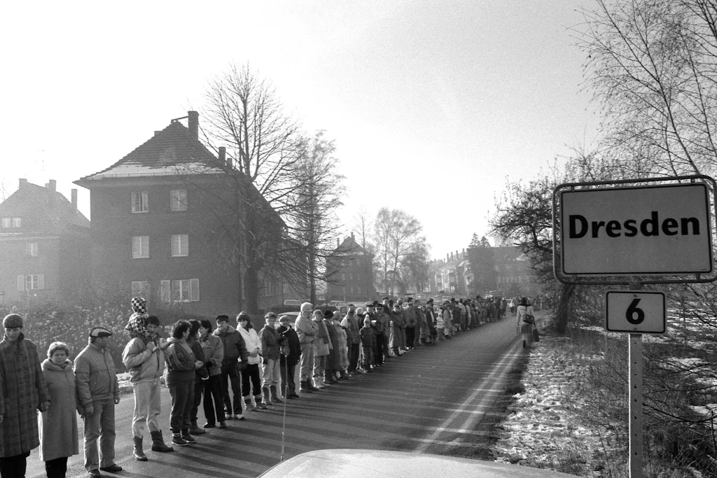 DDR-Bürger demonstrieren im Dezember 1989 an einem Ortseingangsschild in Dresden für Demokratie, Reise- und Pressefreiheit.