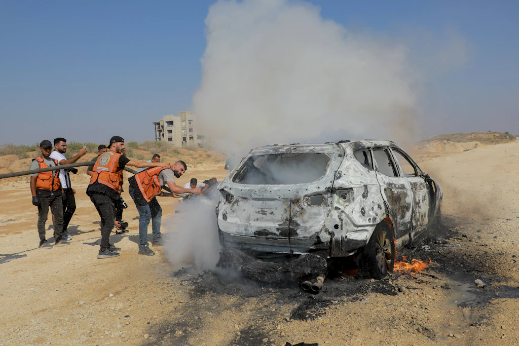 Einsatzkräfte stehen an einem brennenden Fahrzeug nach einem israelischen Luftangriff in Gaza-Stadt am 13. August 2026.