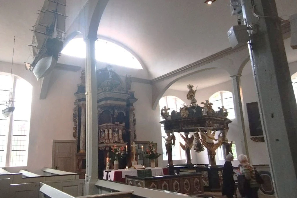 Das Tonnengewölbe krönt ein barocker Kanzelaltar und rechts im Altarraum findet sich eine liebevoll geschnitzte Taufkapelle.  