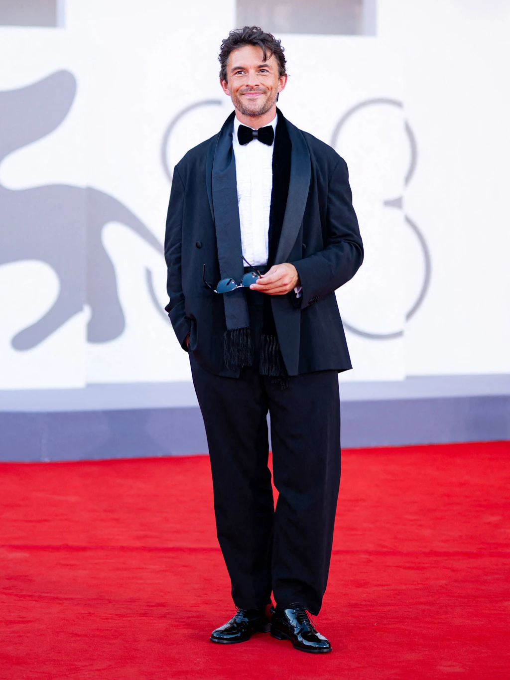 <strong>Top:</strong> Der britische Schauspieler <strong>Jonathan Bailey</strong> macht seinem Titel als „Sexiest Man Alive“, den ihm das <em>People</em>-Magazin 2025 verlieh, alle Ehre und präsentiert sich in einer modern interpretierten Variante des Smokings von Armani. Das Jackett ist locker und leicht oversized geschnitten und fällt ebenso lässig wie die gerade Hose. Dazu trägt Bailey die klassischen Begleiter des Abends: Lackschuhe, schwarze Fliege, weißes Hemd und einen Fransenschal. Wir finden: eine gelungene Weiterentwicklung der klassischen Herrengarderobe – wobei wir bei Jonathan Bailey vielleicht ohnehin etwas befangen sind.