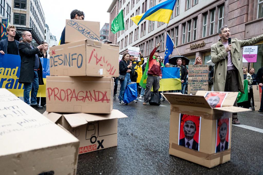Nur wenige Meter weiter schwenken Demonstranten Flaggen der Ukraine. Sie haben Umzugskartons mitgebracht, um dem Russischen Haus symbolisch beim Umzug zu helfen.