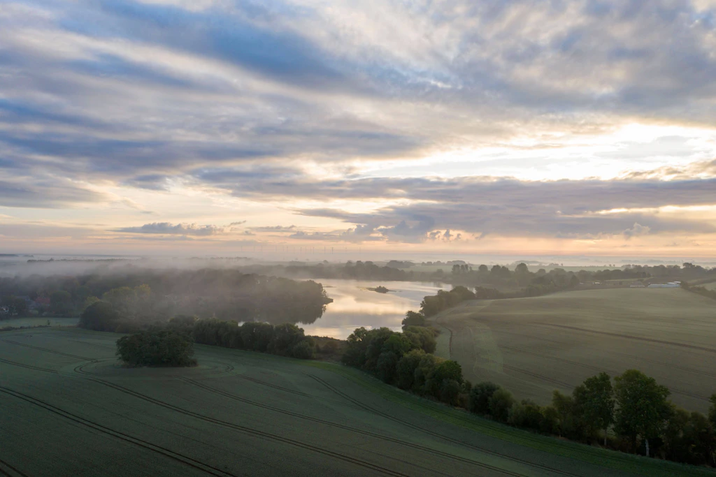 Nebel über einer Flussniederung am frühen Morgen: In der Nacht zum Sonntag sinkt die Sichtweite in der Mitte und im Süden Deutschlands stellenweise unter 150 Meter.