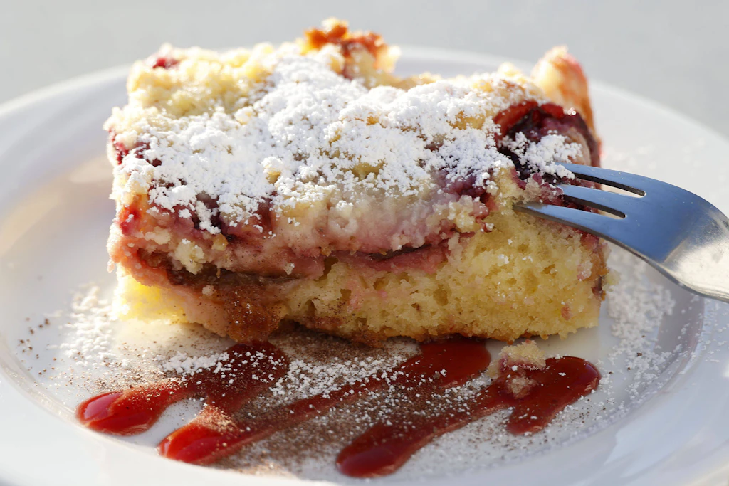 Sie können den fertigen Pflaumenkuchen mit Streuseln auch noch mit etwas Puderzucker bestäuben.