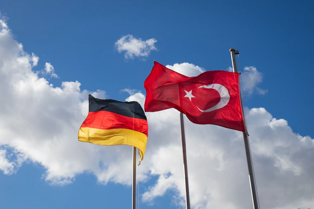 Die deutsche und die türkische Flagge am Fahnenmasten vor einer Moschee.