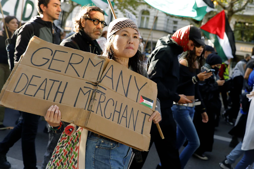Propalästinensische Demonstranten in Berlin. Auf einem Plakat wird Deutschland als „Todeshändler“ bezeichnet, eine Anspielung auf deutsche Waffenlieferungen an Israel.