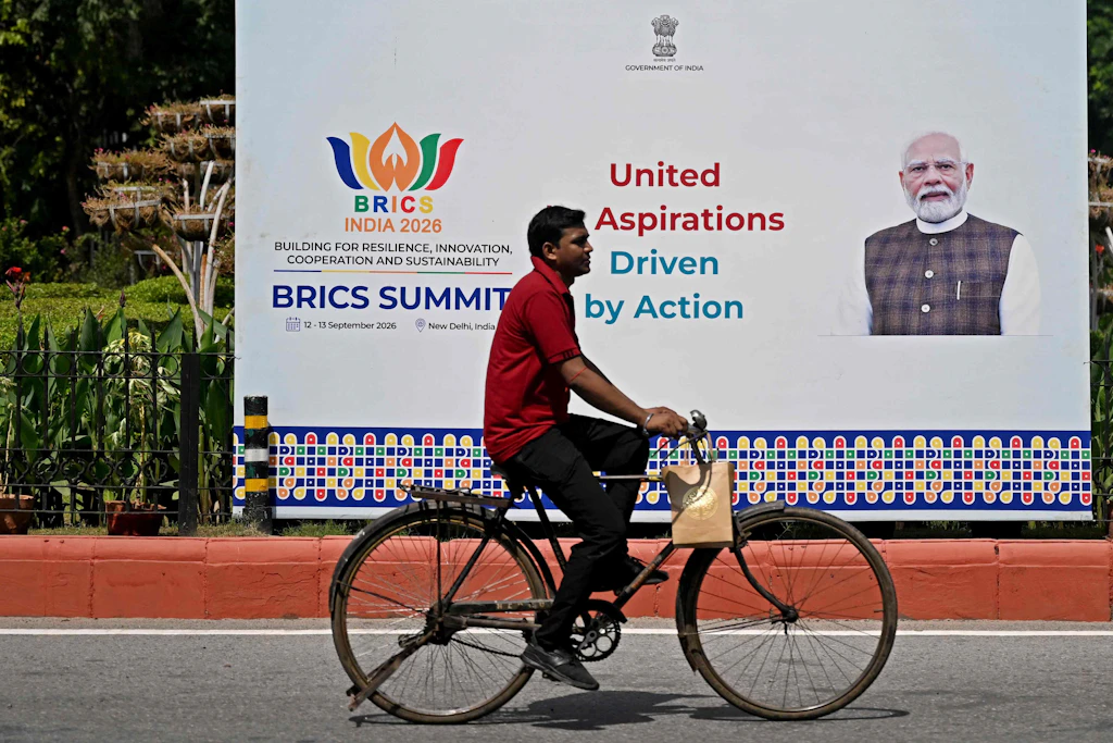 A cyclist rides past a hoarding featuring India