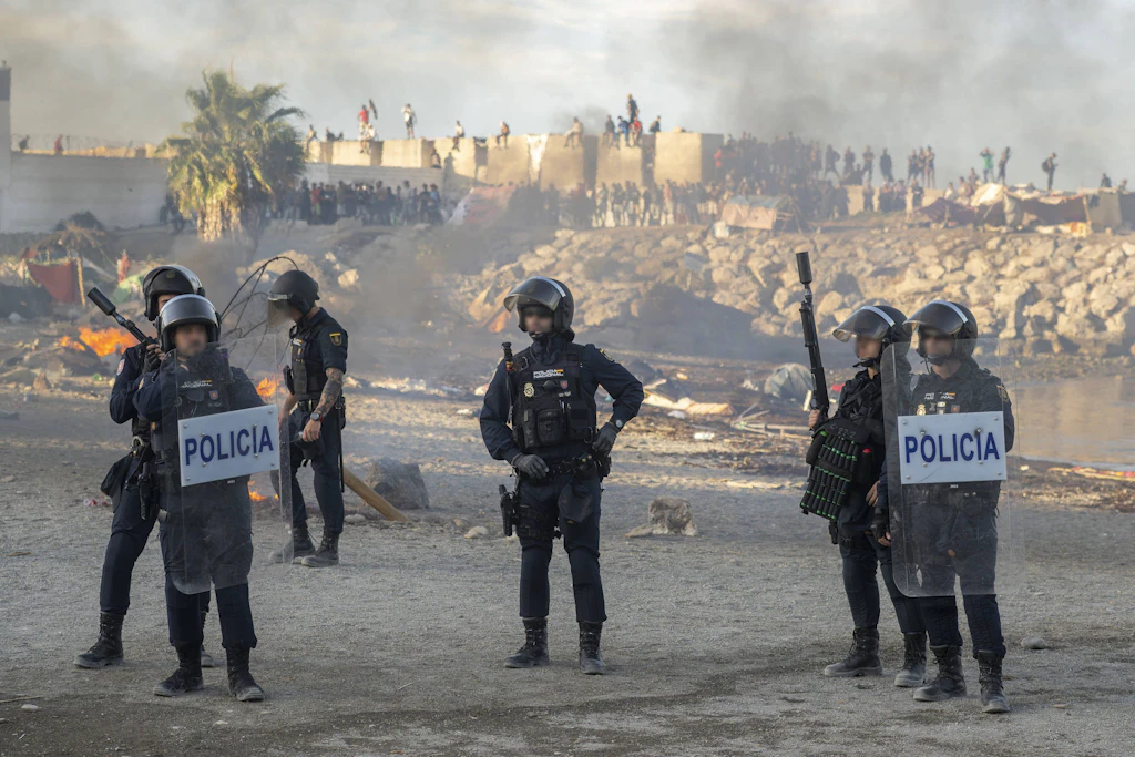 Polizisten sichern eine Protestaktion gegen Migranten in Ceuta. Zuvor waren Unterkünfte beschädigt und persönliche Gegenstände verbrannt worden.