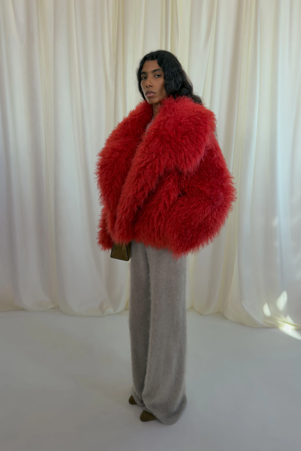 Kräftiges Rot trifft auf klassisches Grau, Fake-Fur auf Wolle. Ein kontrastreicher Look aus der aktuellen Herbst/Winter-Kollektion von Nanushka.
