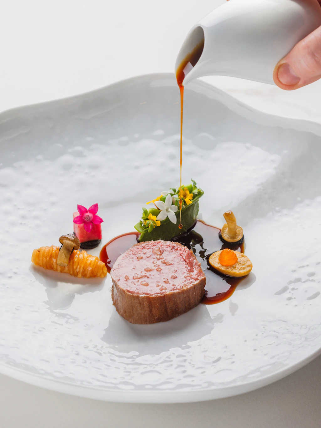 Wagyu-Rind serviert mit Zuckererbsen, Miso, schwarzem Knoblauch und einer klaren Miso-Consommé.