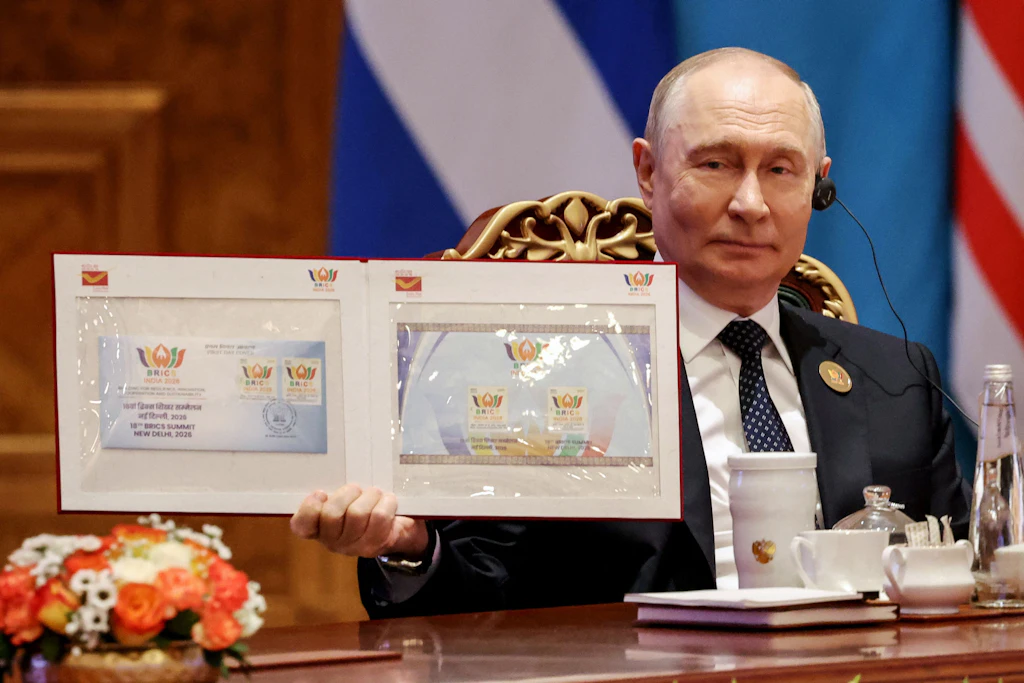 Putin hält eine symbolische Erklärung hoch, um den Abschluss der Einigung für die anwesenden Medien festzuhalten.