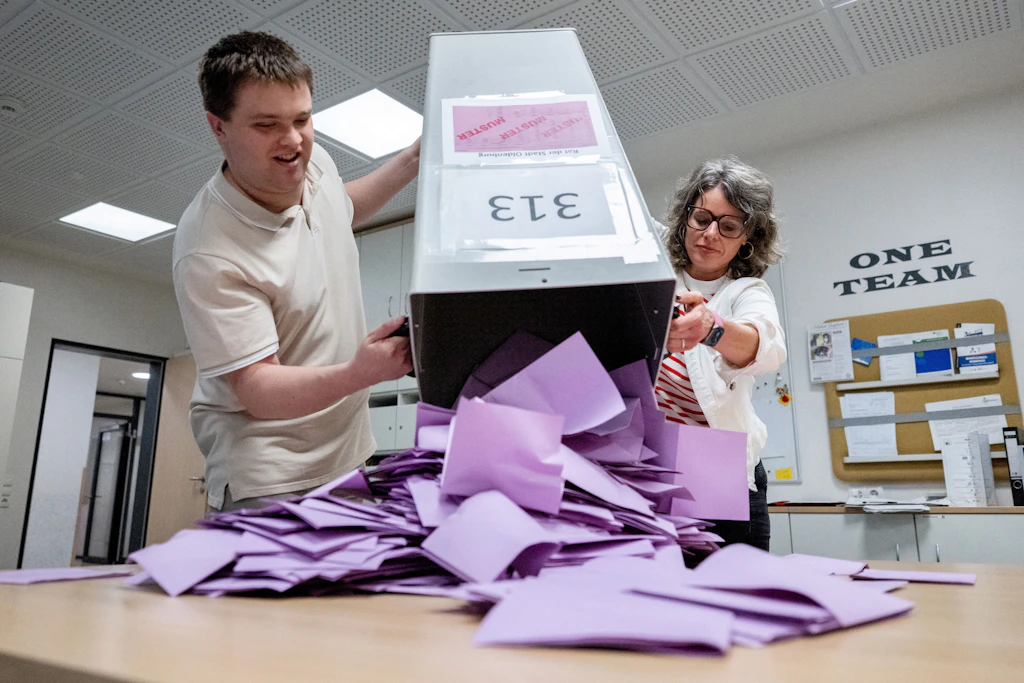 Wahlhelfer entleeren in einem Wahllokal eine Wahlurne mit den Stimmzetteln.