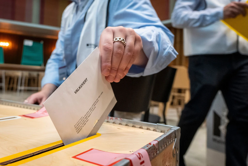 Eine Wählerin wirft in einem Wahllokal im Rathaus von Malmö einen Wahlumschlag in eine Wahlurne.