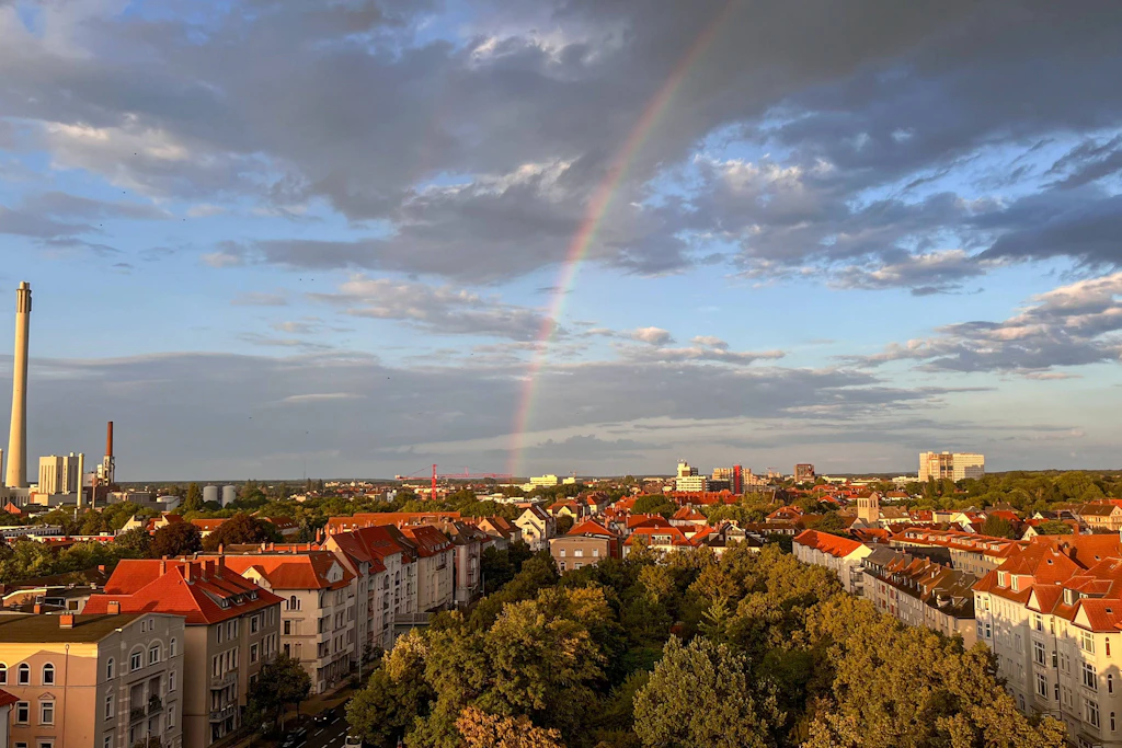 Regenbogen über einer Stadt nach dem Schauer: Am Donnerstag zieht die Kaltfront nach Südosten ab, nur an der Nordsee weht der Wind in Böen bis 70 km/h. (Symbolbild)