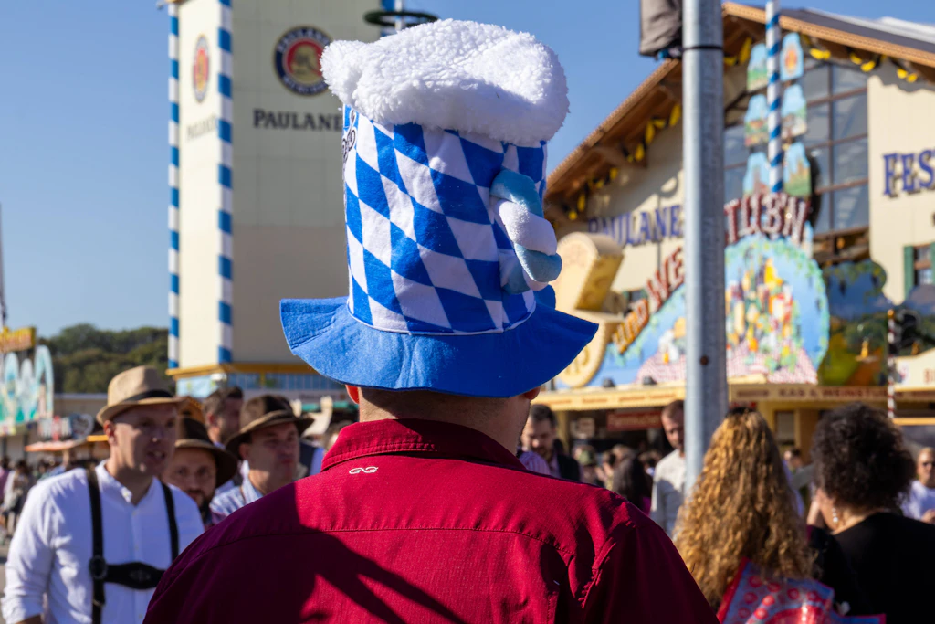 Oktoberfest-Besucher mit Maßkrug-Hut auf der Theresienwiese: Während im Norden Sturm und Graupel drohen, erwartet der DWD in München am Sonntag Sonne und 24 Grad.
