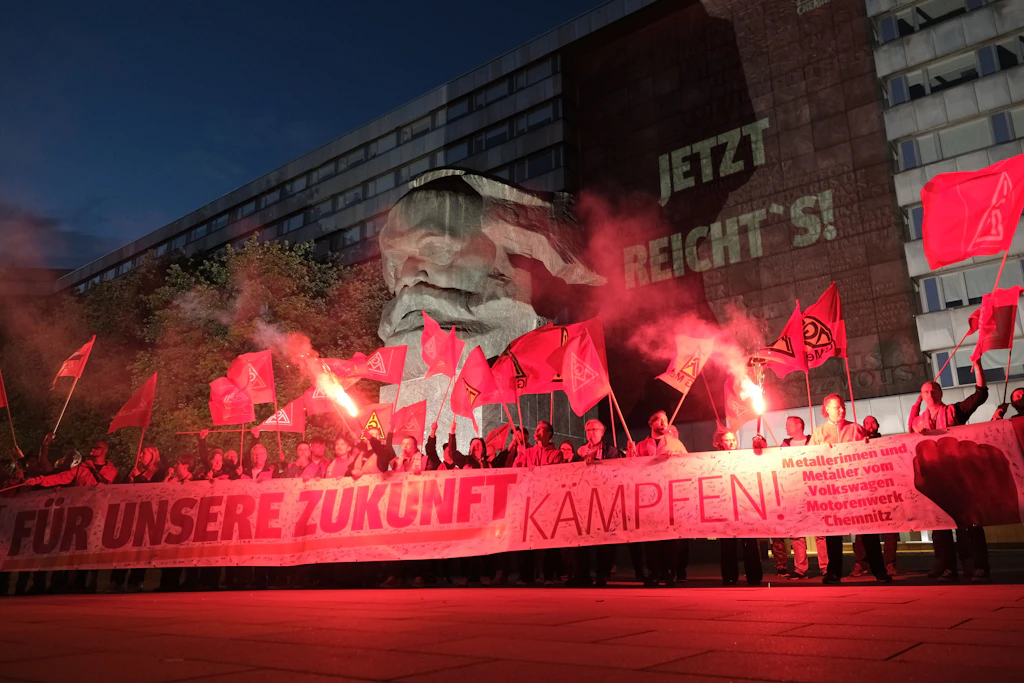 Gewerkschafter der IG Metall versammelten sich mit Transparenten und Pyrotechnik vor dem Karl-Marx-Monument in Chemnitz. Mit der Aktion wollen sie für den Erhalt der Automobilbranche in Sachsen demonstrieren.