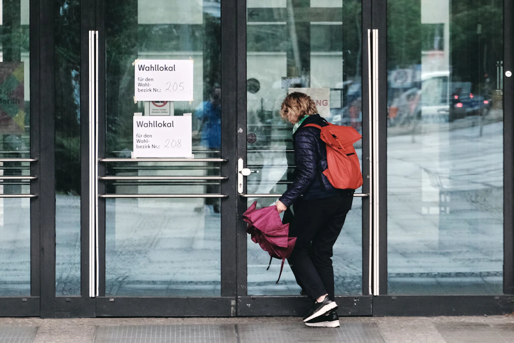 Eine Frau betritt im Regen das Rathaus Mitte an der Karl-Marx-Allee auf dem Weg zum Wahllokal: Wie wirkt sich das Wetter auf die Wahlbeteiligung aus?