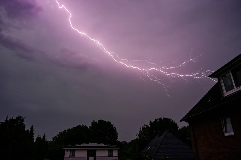 Blitze über einem Wohngebiet: In der Nacht zum Donnerstag ziehen im Norden Deutschlands einzelne Gewitter auf, an der Nordsee warnt der Wetterdienst vor Sturmböen. (Symbolbild)