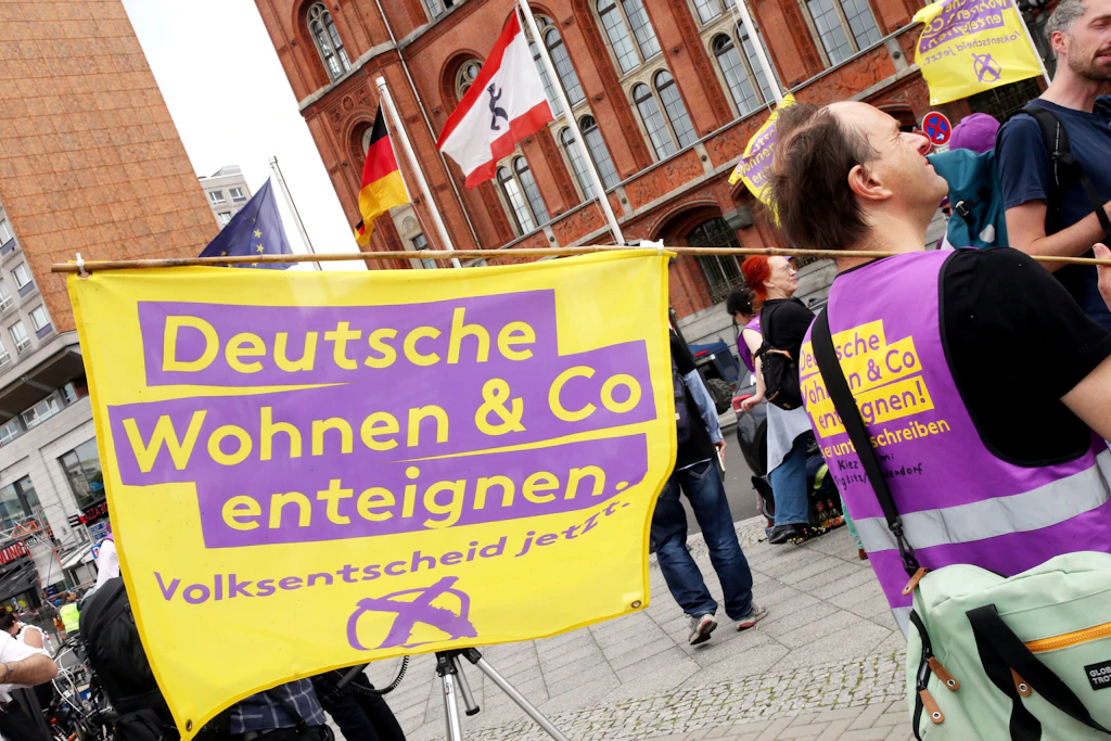 Ein Demonstrant hält eine Fahne mit der Aufschrift „Deutsche Wohnen und Co enteignen“ während einer Kundgebung vor dem Roten Rathaus.